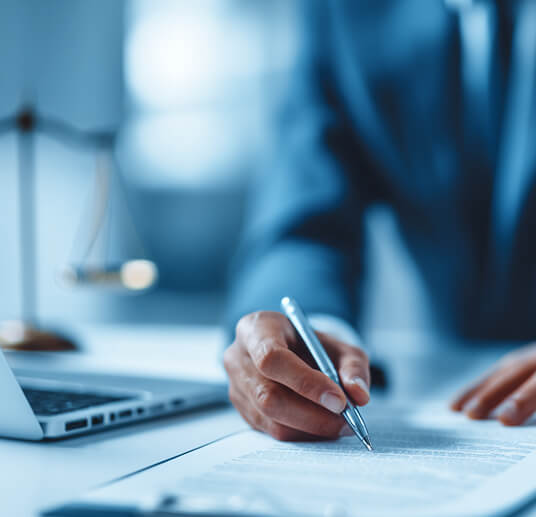 Une personne en costume signe un document sur un bureau